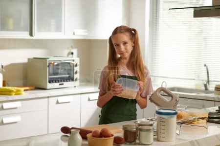 Téléchargez les photos : Portrait d'une adolescente faisant de la pâte à biscuits au comptoir de cuisine - en image libre de droit