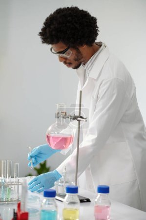Foto de Técnico químico de laboratorio mezclando reactivos cuando trabaja en una solución médica - Imagen libre de derechos