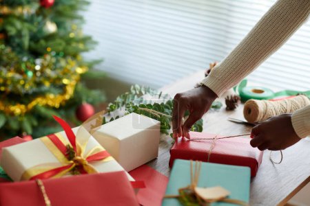 Foto de Manos de mujer decorando envueltos regalos de Navidad con cordel - Imagen libre de derechos