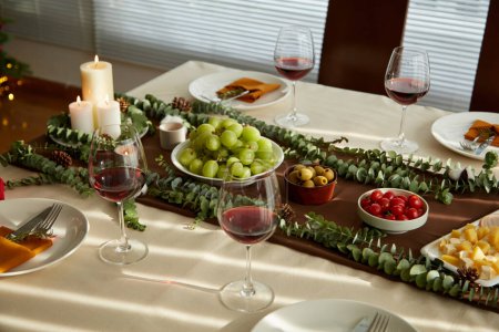 Foto de Mesa de cena de Navidad decorada con aperitivos y copas de vino - Imagen libre de derechos