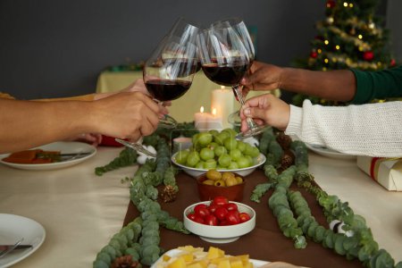 Téléchargez les photos : Amis griller avec des verres à vin sur la table de Noël lors de la célébration à la maison - en image libre de droit