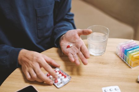 Photo for Hands of person taking painkiller pill with glass of water - Royalty Free Image