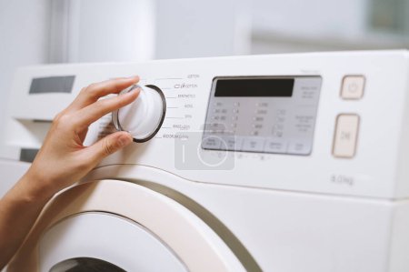 Foto de Imagen de primer plano de la mujer seleccionando la configuración de la lavadora para la ropa - Imagen libre de derechos