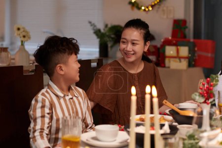 Téléchargez les photos : Mère et fils souriants assis à la table de Noël - en image libre de droit
