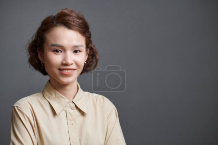 Photo for Cheerful young smiling Vietnamese businesswoman, isolated on grey - Royalty Free Image