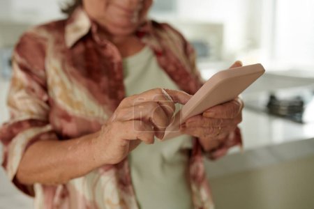 Téléchargez les photos : Image rapprochée de la femme âgée vérifiant les notifications sur smartphone - en image libre de droit