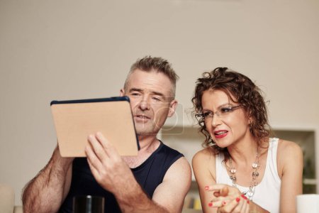Photo for Glam rock mature couple making video call via application on tablet computer - Royalty Free Image