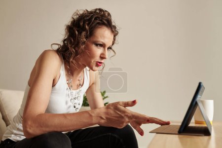 Photo for Emotional stylish mature woman watching shocking news on digital tablet - Royalty Free Image