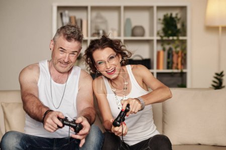 Photo for Joyful excited middle-aged couple playing racing videogame at home - Royalty Free Image