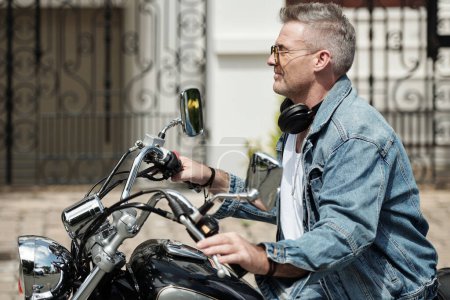 Foto de Vista lateral del hombre de mediana edad que monta en motocicleta en la ciudad - Imagen libre de derechos