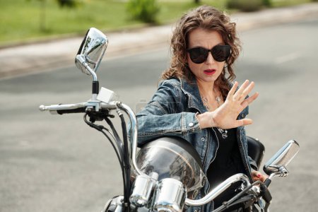 Foto de Mujer madura infeliz sentada en motocicleta y mirando las manos bien cuidadas - Imagen libre de derechos
