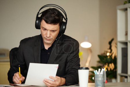 Photo for Serious lawyer in headset revising contract for client and making corrections - Royalty Free Image