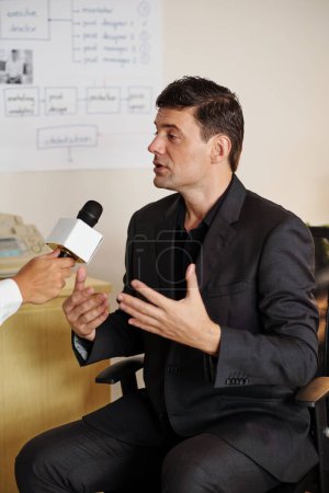 Foto de Propietario del negocio respondiendo preguntas del entrevistador con micrófono - Imagen libre de derechos