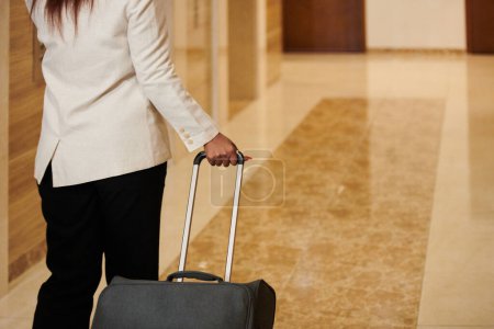 Foto de Imagen recortada de una mujer negra con una maleta grande caminando a su habitación de hotel - Imagen libre de derechos