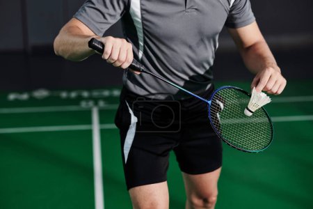 Photo for Cropped image of fit young man serving shuttlecock when playing game with friend - Royalty Free Image