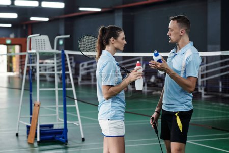 Téléchargez les photos : Joueurs de badminton professionnels boire de l'eau et discuter du jeu - en image libre de droit