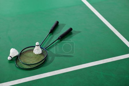 Téléchargez les photos : Navettes et raquettes de badminton sur le parquet vert - en image libre de droit