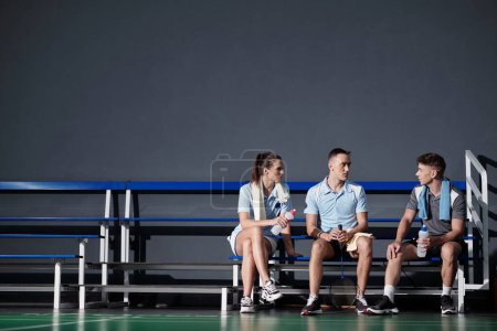Téléchargez les photos : Badminton joueurs reposant sur le banc après le match, boire de l'eau et discuter des erreurs - en image libre de droit