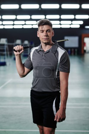 Téléchargez les photos : Portrait d'un jeune sportif sérieux posant avec une raquette de badminton - en image libre de droit