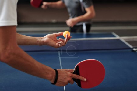 Foto de Manos de hombre joven sirviendo pelota de ping pong con topspin - Imagen libre de derechos