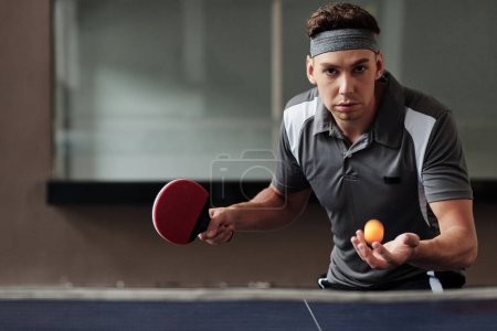 Foto de Retrato de deportista serio determinado sirviendo pelota en juego de tenis de mesa - Imagen libre de derechos