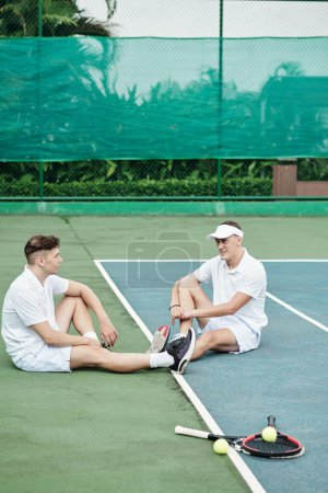 Photo for Positive players resting after game of tennis on outdoor court - Royalty Free Image