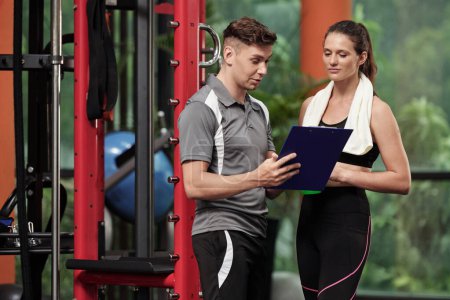 Photo for Fitness coach talking to fit female client when explaining new training plan - Royalty Free Image