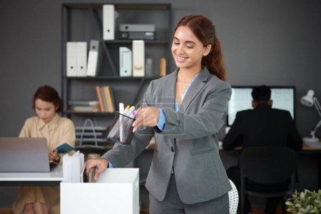 Photo for Excited young businesswoman putting belongings on desk in new office - Royalty Free Image