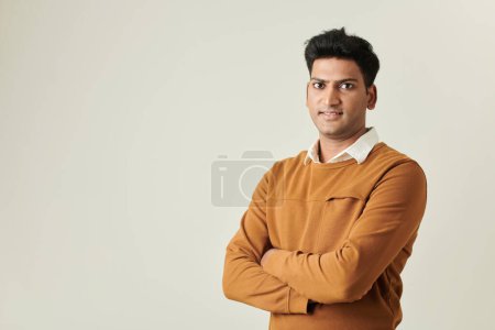 Téléchargez les photos : Portrait d'un homme d'affaires indien souriant en pull moutarde croisant les bras et regardant la caméra - en image libre de droit