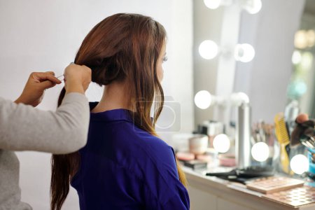 Téléchargez les photos : Jeune femme se faire épingler les cheveux dans le dos dans le salon de beauté - en image libre de droit