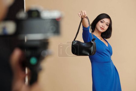 Photo for Fashion catalog model photographing with small faux leather bag - Royalty Free Image