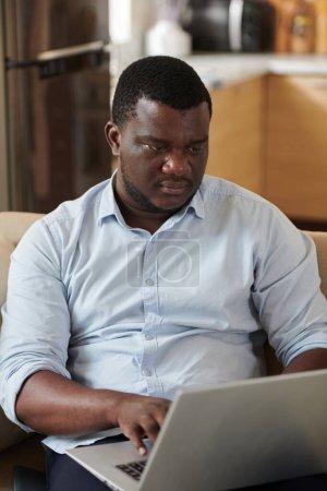 Téléchargez les photos : Serious Black développeur de logiciels de codage sur ordinateur portable à la maison - en image libre de droit