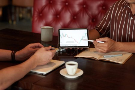 Téléchargez les photos : Mains de commerçants crypto discuter graphique du marché boursier sur tablette lors de la réunion dans le café - en image libre de droit
