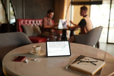 Photo for Tablet with chart on screen, earbuds, planner and cup of espresso on cafe table - Royalty Free Image