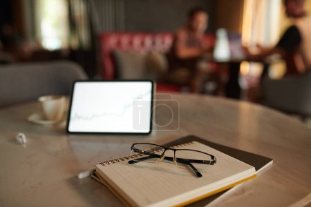 Téléchargez les photos : Lunettes sur pile de planificateurs à côté de tablette numérique sur table en coffeeshop - en image libre de droit