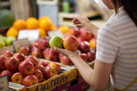 Téléchargez les photos : Jeune femme achetant des fruits frais biologiques au marché local - en image libre de droit