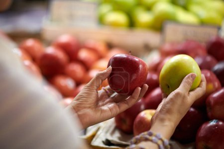 Téléchargez les photos : Mains du client choisir entre les pommes rouges et vertes lors des achats au marché - en image libre de droit
