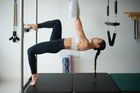 Téléchargez les photos : Fit jeune femme faisant l'exercice complet du corps dans la machine spéciale - en image libre de droit