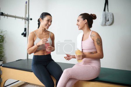 Photo for Smiling fit young sportswomen having vitamin drinks after training together - Royalty Free Image