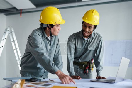 Photo for Diverse team of construction workers discussing changes in building blueprint - Royalty Free Image