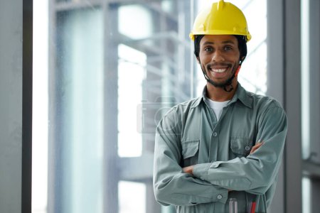 Téléchargez les photos : Portrait d'un travailleur de la construction souriant et confiant en casque rigide et gris dans l'ensemble - en image libre de droit