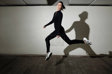 Téléchargez les photos : Portrait de jeune danseuse en costume noir regardant la caméra pendant son interprétation en studio - en image libre de droit