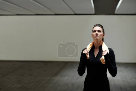 Photo for Young fit girl in black sport clothing standing at studio and resting after training - Royalty Free Image