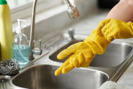 Foto de Primer plano de la joven en guantes de protección lavar los platos en el fregadero en la cocina - Imagen libre de derechos