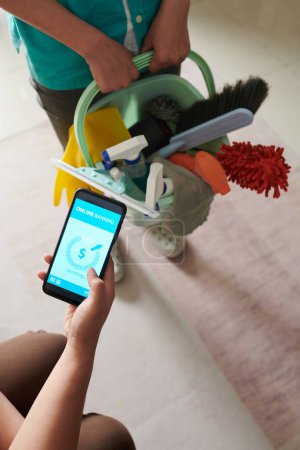 Téléchargez les photos : Gros plan de la cliente qui paie son service de nettoyage en ligne à l'aide de son téléphone mobile - en image libre de droit