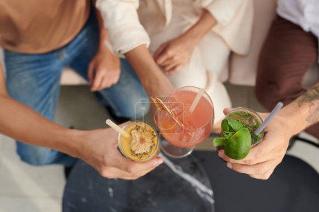 Téléchargez les photos : Mains de jeunes qui claquent des verres de cocktails de fruits - en image libre de droit