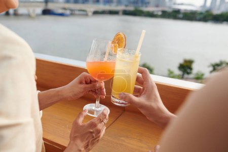 Téléchargez les photos : Mains de jeunes gens griller avec des verres à cocktails à la fête sur le toit - en image libre de droit