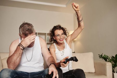 Photo for Sad ashamed mature man loosing videogame to his happy excited girlfriend - Royalty Free Image