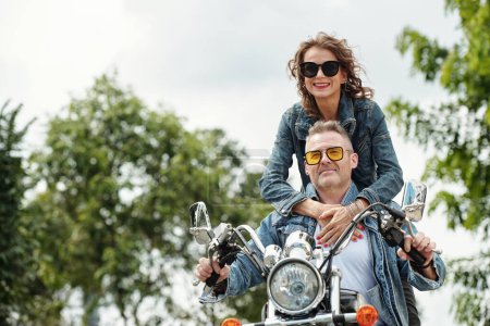 Photo for Cool happy mature couple in demin jackets riding motorbike in city - Royalty Free Image
