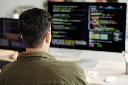 Téléchargez les photos : Développeur de logiciels regardant le code de programmation sur l'écran de l'ordinateur, vue de dos - en image libre de droit